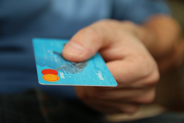 person presenting a blue credit card